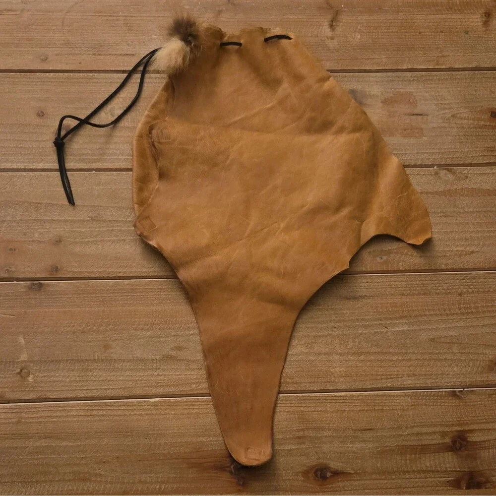 Handcrafted tan leather drawstring pouch featuring a soft fur pom-pom